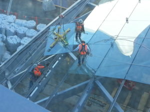 Robertson helps design train stations and makes sure they're dry and safe for Denver's commuters. Construction workers placing glass on a steel frame.