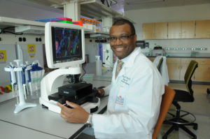Bioengineer Derek West, examining cells with a fluorescence microscope. Photo by Dwight C. Andrews / The University of Texas Medical School at Houston, Office of Communications.